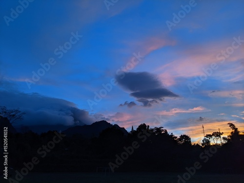 The beauty of sunrise on a field with mountains and clouds in the background