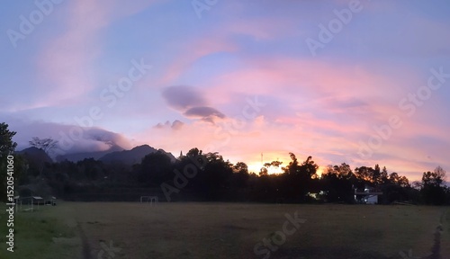The beauty of sunrise on a field with mountains and clouds in the background