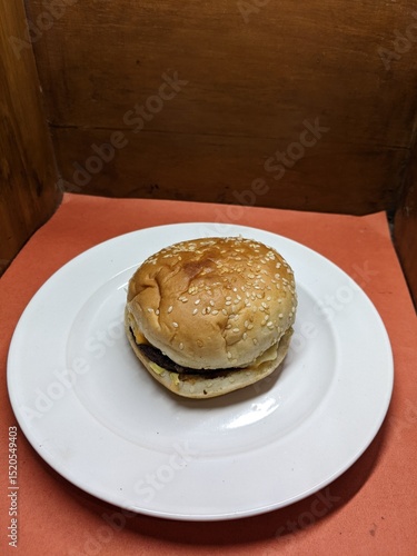 Mini burger on a white plate, with a wood and orange background