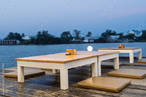 A wooden table with a white tablecloth and a few chairs with cushions