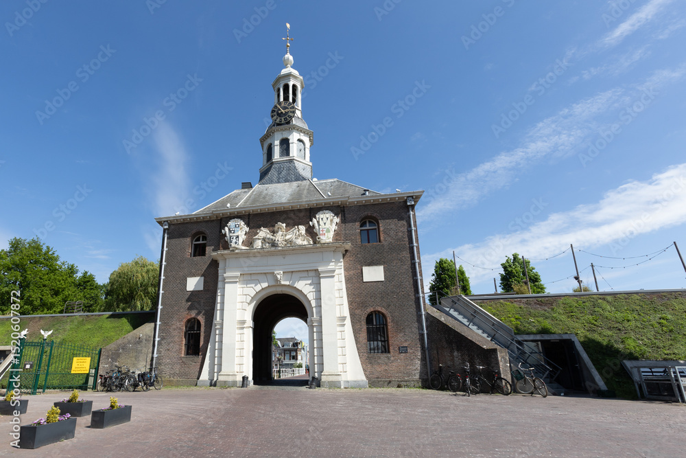 Fototapeta premium The historic Zijlpoort gate in Leiden, Netherlands, a prominent city landmark with its elegant architecture and clock tower, bathed in sunlight.