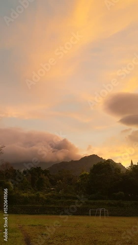 The beauty of sunrise on a field with mountains and clouds in the background
