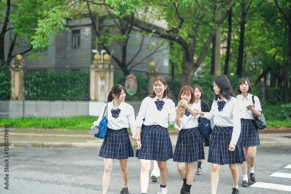 Obraz premium On a bright early summer morning in Pudong, Shanghai, seven Japanese high school girls wearing crisp summer uniforms are chatting as they cross a busy city street crosswalk on their way to school.