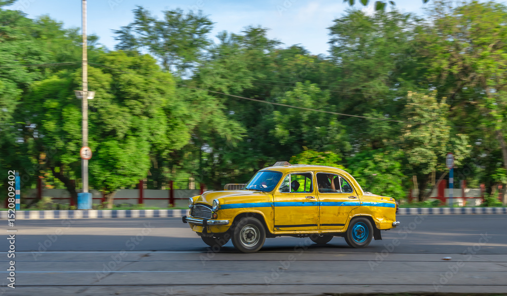 Obraz premium West Bengal, India. May 26,2025. Motion Blue Image of a Yellow Taxi in Kolkata City.