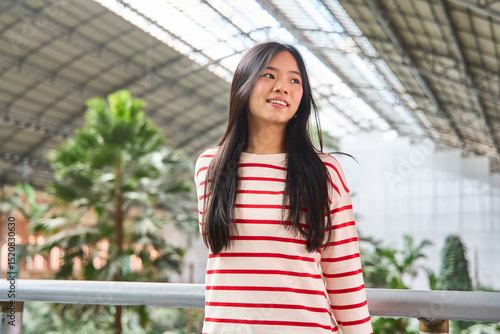 Young asian woman smiling in atocha station madrid,