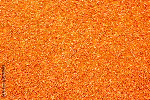Here is a detailed close up image of a vibrant pile of orange glitter