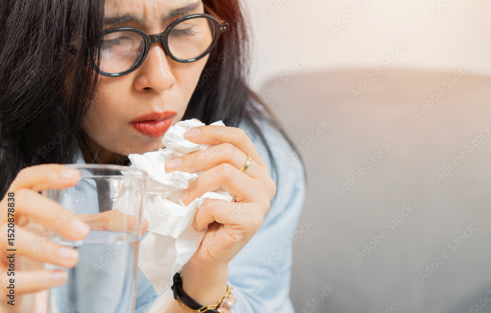 Close-up part of female holding glass of water and tissue while coughing because of a sore throat. Close-up part of female holding glass of water and tissue while coughing because of a sore throat.