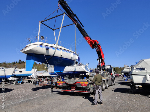Foto A sailboat lifted by a crane in Suomenoja harbor in Espoo, Finland
