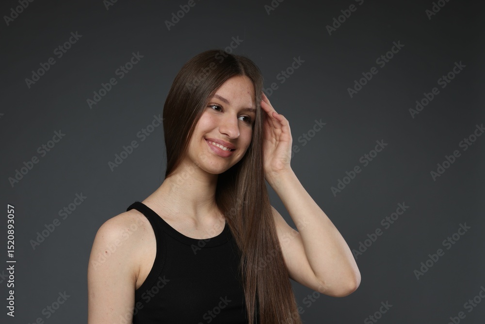 Portrait of smiling teenage girl with healthy long hair on dark grey background Portrait of smiling teenage girl with healthy long hair on dark grey background