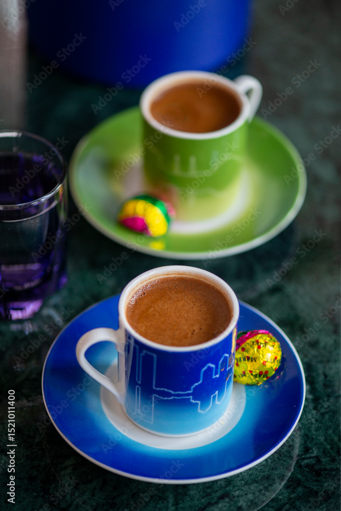 Fototapeta premium A welcome gesture at a hotel, Turkish coffee for two with chocolate and water on a marble tabletop in a hotel room setting with soft window light