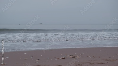 Watch as the cloudy sunrise casts a soft glow over Portobello Beach, highlighting the tranquil waves lapping against the shore.