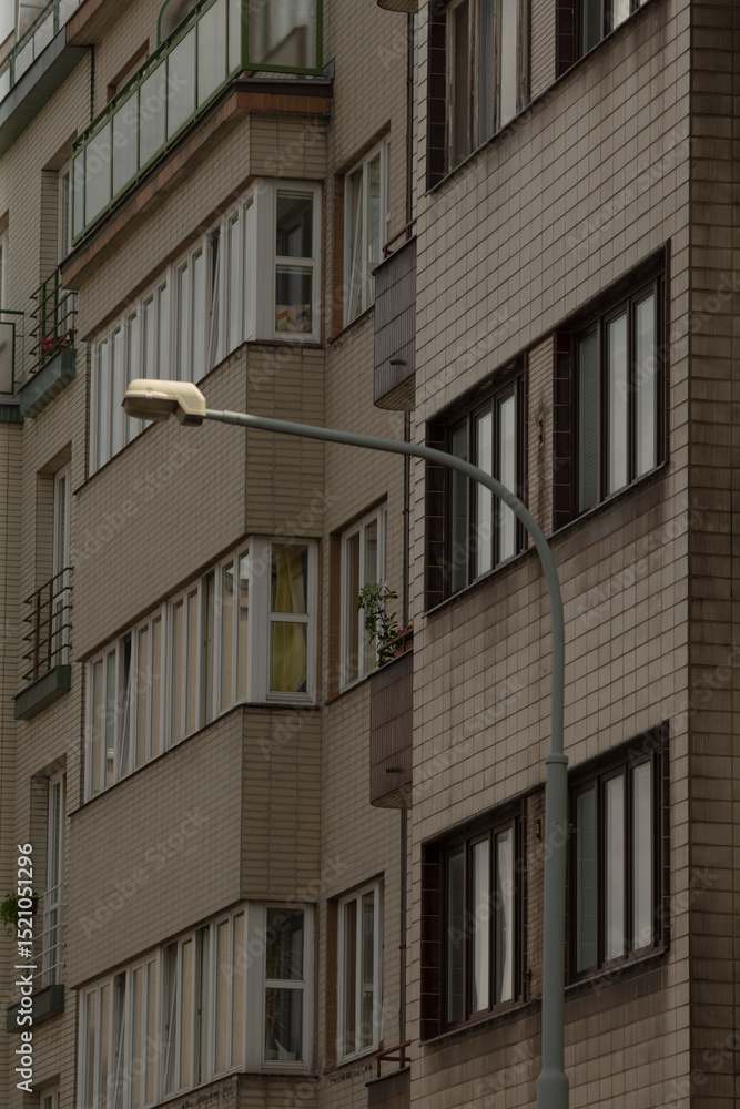 An exterior view shows a contemporary urban apartment building that boasts numerous large windows. In the foreground, theres a street lamp that contributes to the urban landscape ambiance An exterior view shows a contemporary urban apartment building that boasts numerous large windows. In the foreground, theres a street lamp that contributes to the urban landscape ambiance