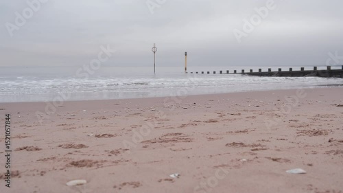EDINBURGH, SCOTLAND, UK - JANUARY 5, 2024: Experience a peaceful morning at Portobello Beach with a cloudy sunrise illuminating the calm waters and gentle waves against the shore with a breakwater.