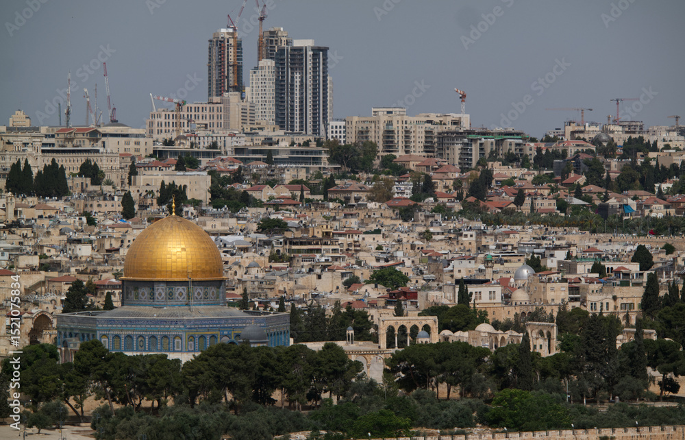 Fototapeta premium Panoramic view of the Dome of the Rock in Jerusalem, Israel, with the golden dome prominently visible against the densely built historic and modern cityscape. 