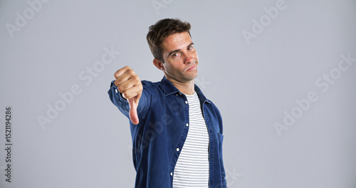 Foto Man, portrait or thumbs down in studio for no, disapproval or disagree on a background