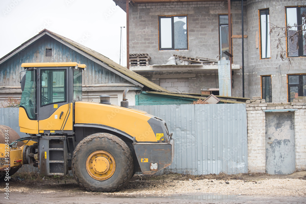 Obraz premium Construction equipment parked near a building site in an urban area during cloudy weather