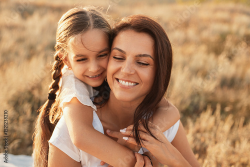 Canvas Print A beautiful, candid moment of a smiling mother and daughter embracing together in a rustic outdoor setting, showcasing love, connection, and natural serenity during a sunlit day