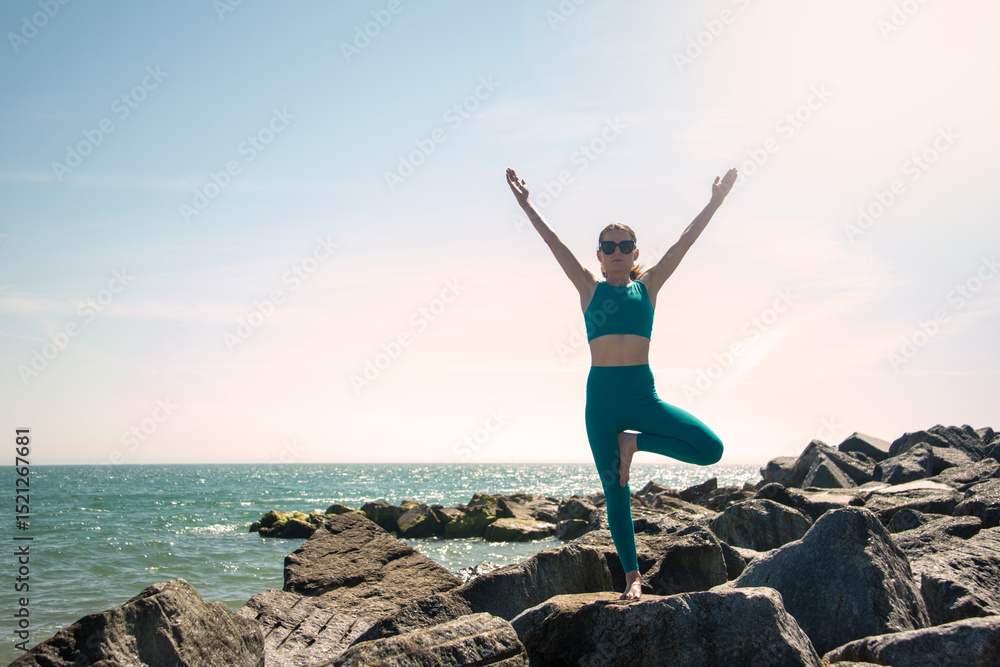sporty woman standing on rocks doing yoga a tree pose sporty woman standing on rocks doing yoga a tree pose