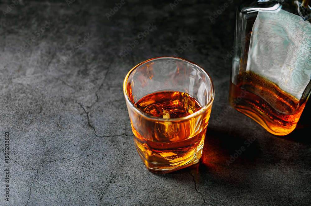 Fototapeta premium Strong alcohol drink and whiskey bottle Whisky in glass with ice, Whisky, bourbon or cognac. Hard strong alcoholic drink