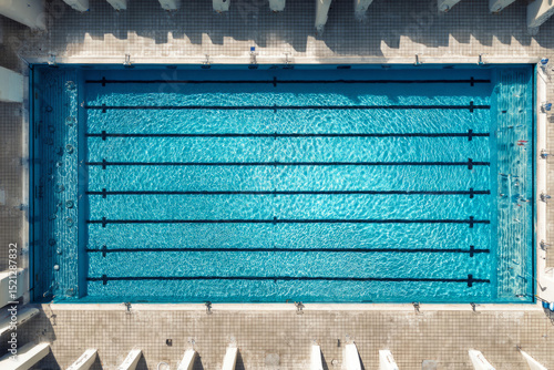 Wallpaper Mural Aerial view of an empty Olympic-size swimming pool with clear blue water and black lane dividers, surrounded by tiled deck in bright daylight — ai generative. Torontodigital.ca