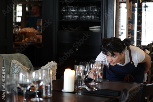 Serveuse concentrée lors du dressage d'une table élégante au restaurant