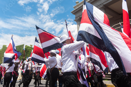 Students wave Costa Rican flags in a coordinated movement during a vibrant Independence Day celebration. 