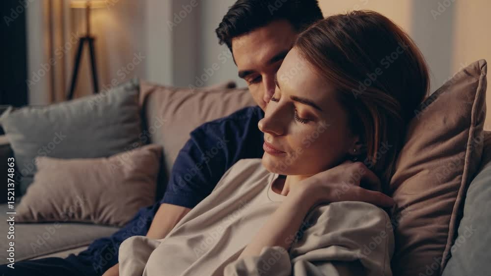 Loving couple sharing intimate moment, gently embracing while sitting close together on soft living room sofa, expressing deep emotional connection and mutual affection Loving couple sharing intimate moment, gently embracing while sitting close together on soft living room sofa, expressing deep emotional connection and mutual affection