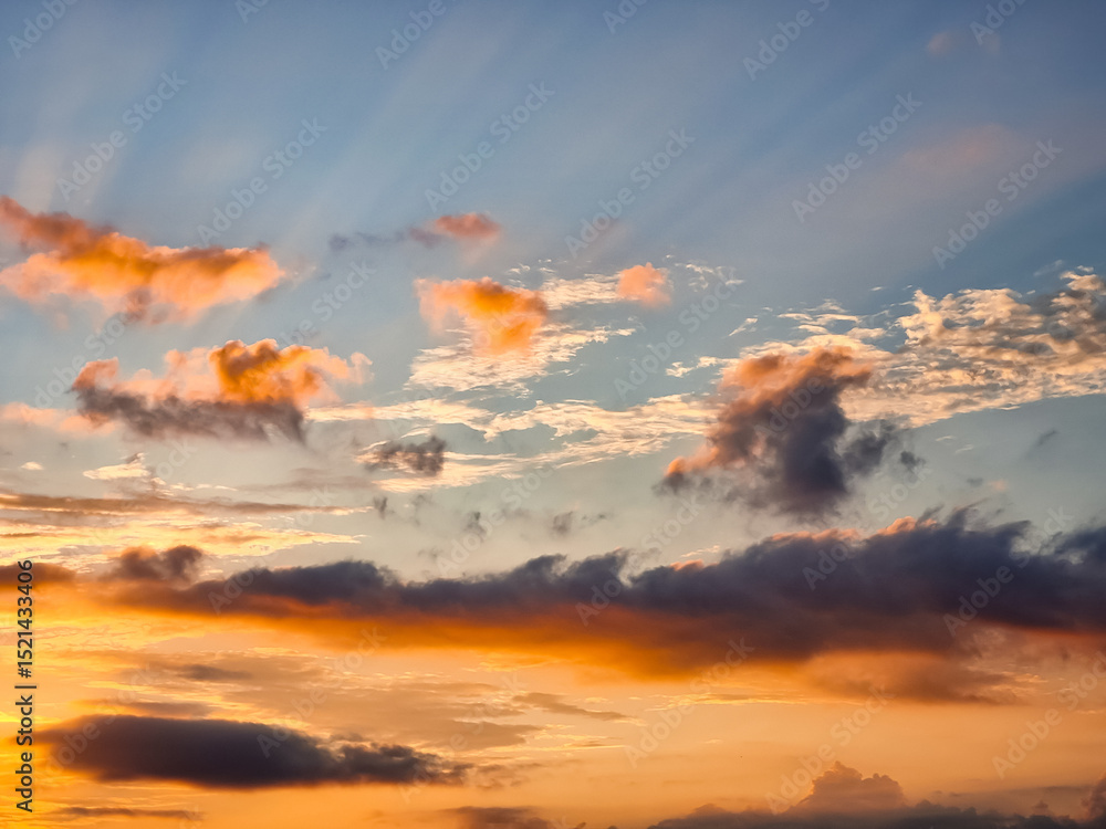 Fototapeta premium Golden sunset clouds with soft sunlight rays and colorful sky during a peaceful evening