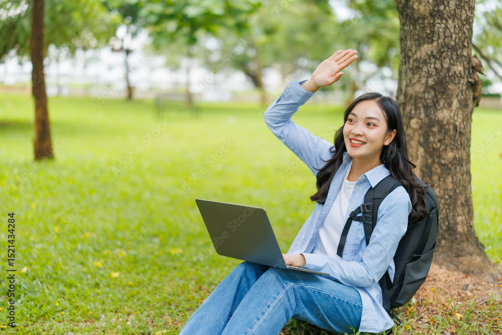 University student waving cheerfully to a friend while working on a laptop in a vibrant green park, relishing the fresh air and the beauty of the natural surroundings University student waving cheerfully to a friend while working on a laptop in a vibrant green park, relishing the fresh air and the beauty of the natural surroundings