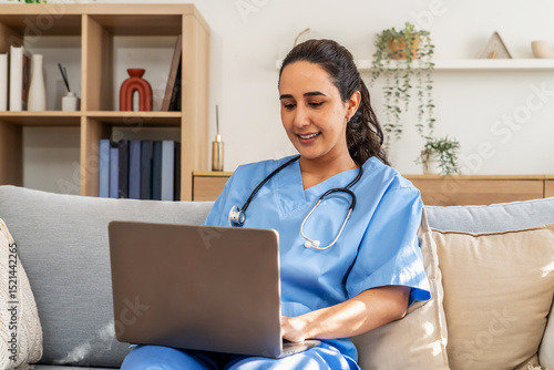 In a cozy living room, a healthcare professional or nurse sits on a sofa, diligently typing on a laptop late in the evening.