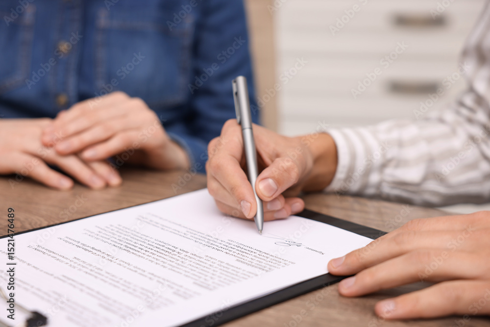 Man putting signature on document at table, closeup Man putting signature on document at table, closeup