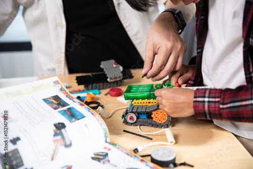 Close-up of a person's hands diligently assembling a colorful robot from construction blocks, guided by an open instruction manual.