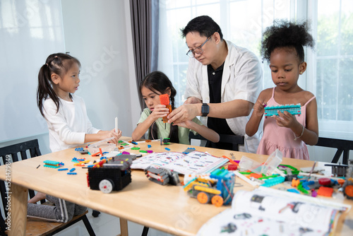 A male teacher guides three young girls as they engage in a creative and educational activity, building with colorful construction toys at a table.