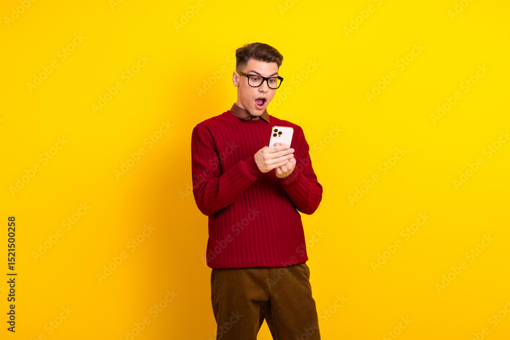 Handsome Young Handsome Man in Stylish Red Sweater Looking Surprised at Smartphone Over Yellow Background Handsome Young Handsome Man in Stylish Red Sweater Looking Surprised at Smartphone Over Yellow Background