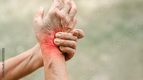 Close up of senior hand gripping inflamed wrist in pain with red highlighted area indicating joint injury or arthritis