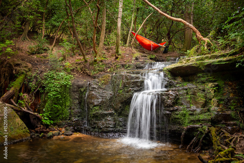 Tableau sur toile One person hammock outdoors camping above waterfall in forest at F