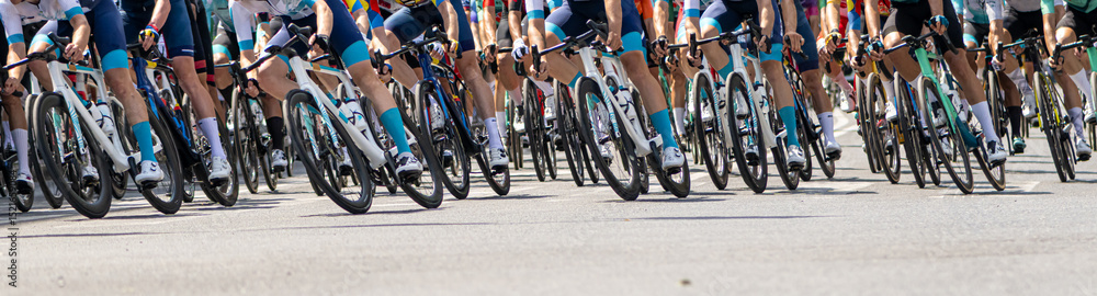 Fototapeta premium Professional cyclists in vibrant uniforms racing outdoors during a high-energy competition with close-up focus on their bicycles in motion.