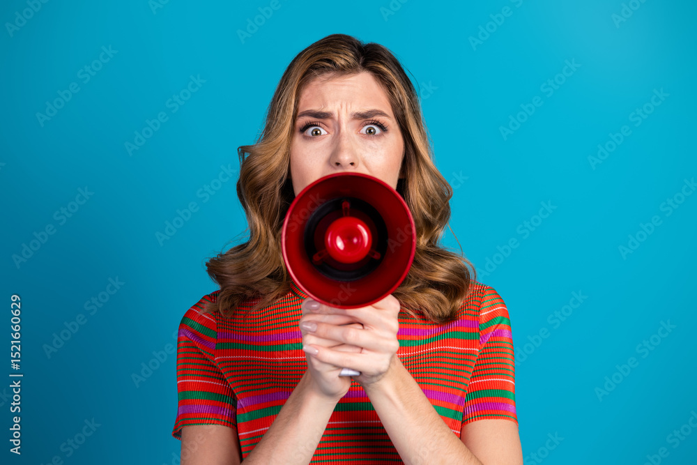 Obraz premium Focused young woman holding a red megaphone against a blue background expressing enthusiasm and energy