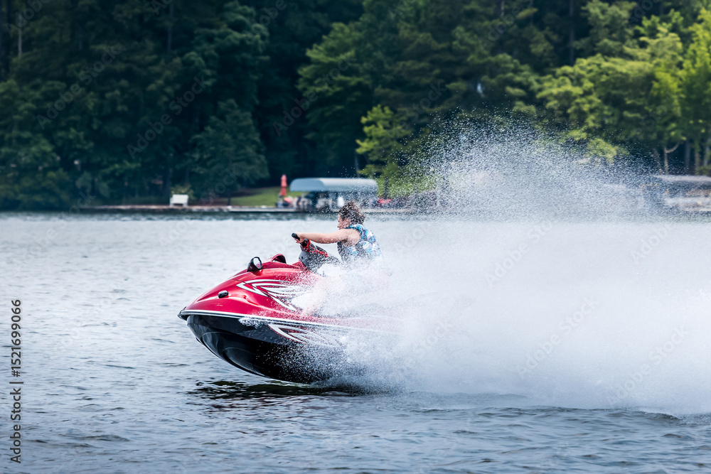 Fototapeta premium Teenage boy riding jet ski personal watercraft and enjoying summer day on lake.