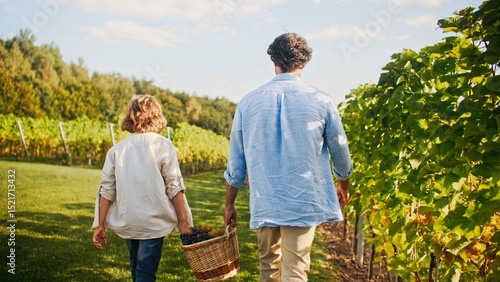 Camera following two men. People helping each other during harvest season. Dad teaching son basics of family business. Farmers collecting grapes. Gently touching leaves of green plants with hand.
