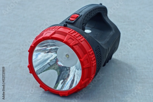one big powerful new round plastic switched off with white reflector battery operated electric with handle big black flashlight lies on the gray table