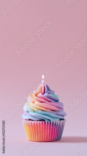 Colorful Rainbow Cupcake With a Candle Against a Soft Pink Background.