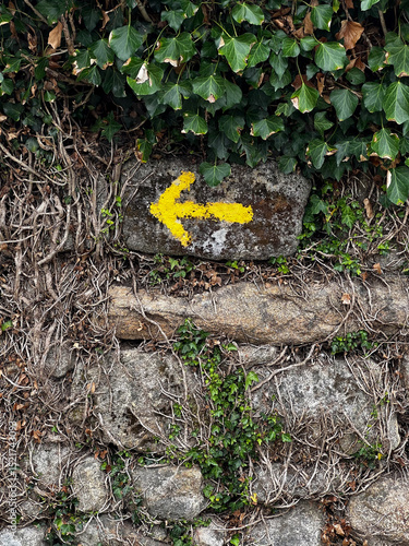 yellow arrow sign pointing left in portugal on the camino de Santiago, the road to santiago, christian pilgrimage in Spain and portugal