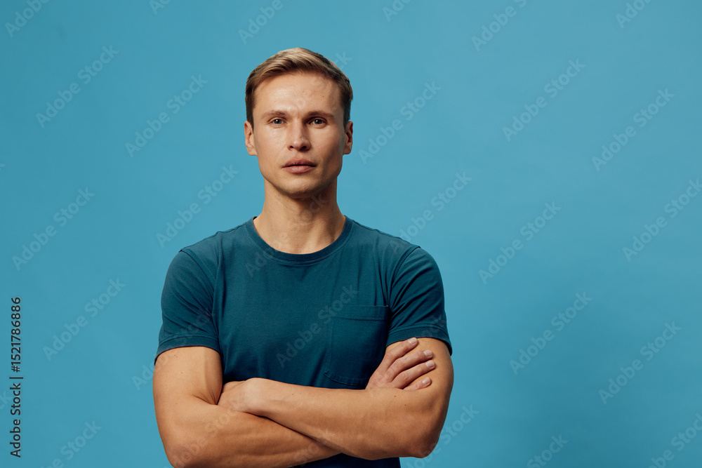 serious man arms crossed blue t-shirt studio portrait confident caucasian adult standing plain background modern casual lifestyle concept serious man arms crossed blue t-shirt studio portrait confident caucasian adult standing plain background modern casual lifestyle concept