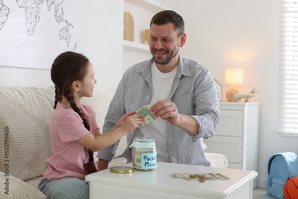 Fototapeta premium Father giving his daughter pocket money at table indoors