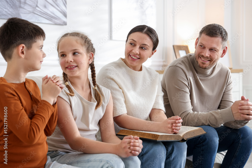Fototapeta premium Family with Bible praying together at home