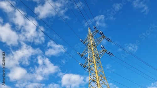 Timelapse of high voltage electrical transmission tower and power lines against blue cloudy sky.