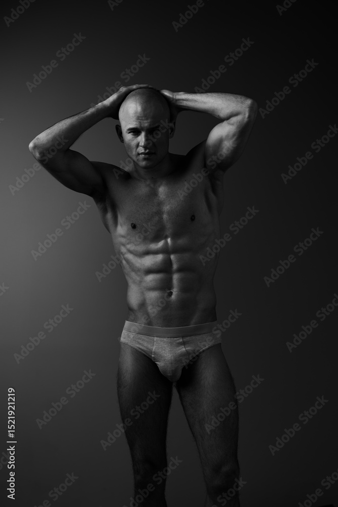 Naklejka premium Athletic man showcasing a powerful physique in a stunning black and white portrait, emphasizing strength and confidence in a minimalist style.