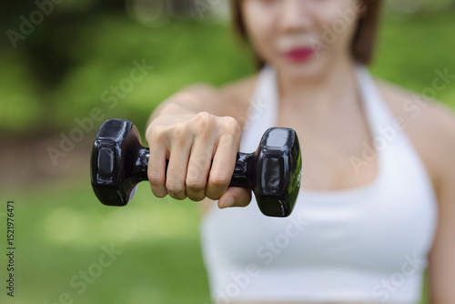 Fotografía A determined individual confidently holds a dumbbell in a sunny park, showcasing strength and resilience, emphasizing the importance of fitness and healthy living in daily life