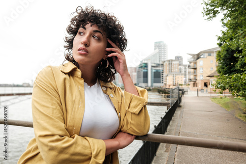 Εκτύπωση καμβά Young woman leaning on railing by river contemplating future